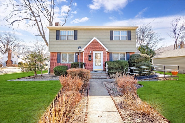 colonial-style house featuring a front yard, brick siding, and a chimney