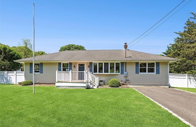 ranch-style house featuring driveway, a front lawn, and fence