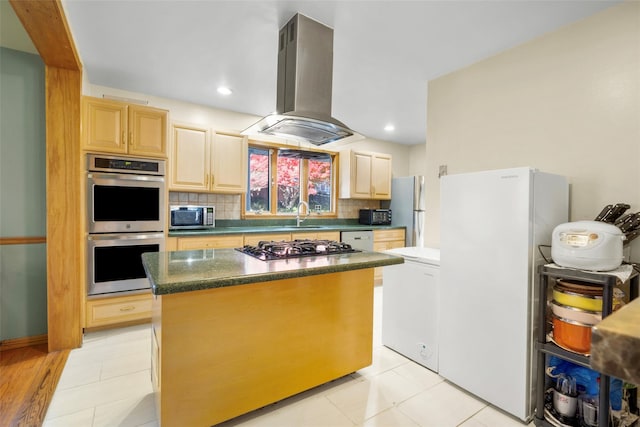 kitchen with light brown cabinets, island range hood, appliances with stainless steel finishes, backsplash, and dark countertops