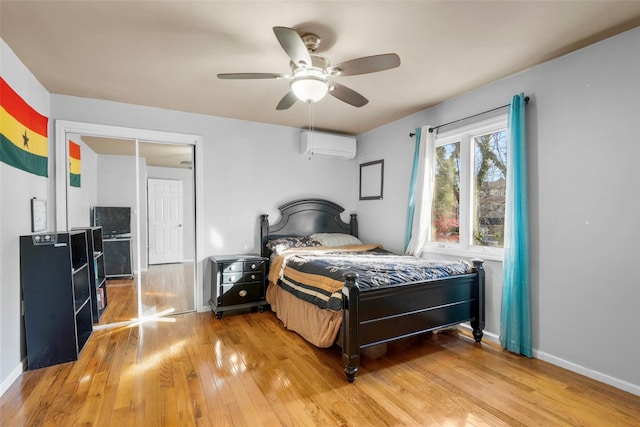 bedroom with ceiling fan, light wood-style flooring, baseboards, and a wall mounted AC