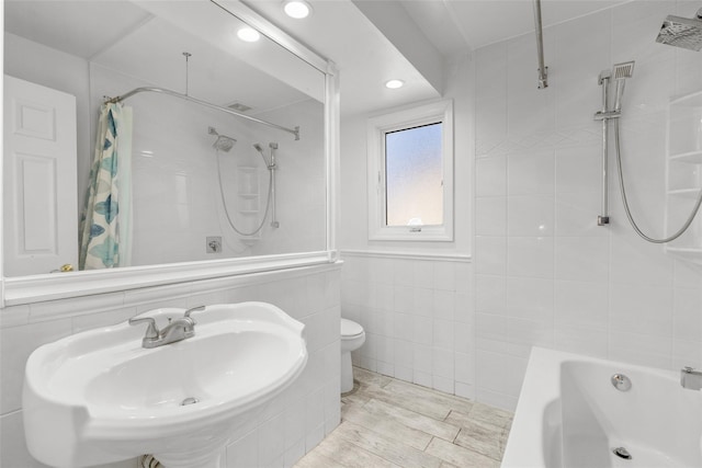 full bathroom featuring toilet, wood finished floors, shower / tub combo with curtain, a sink, and tile walls