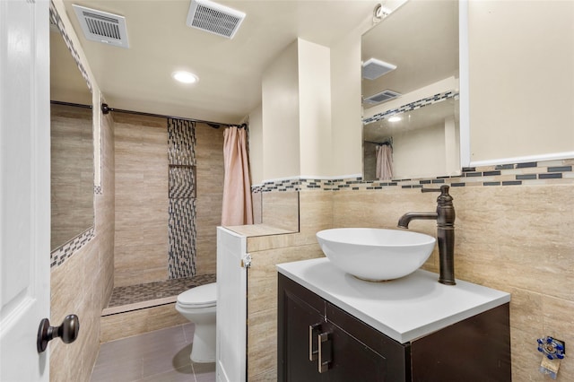 full bathroom featuring a tile shower, visible vents, and tile walls