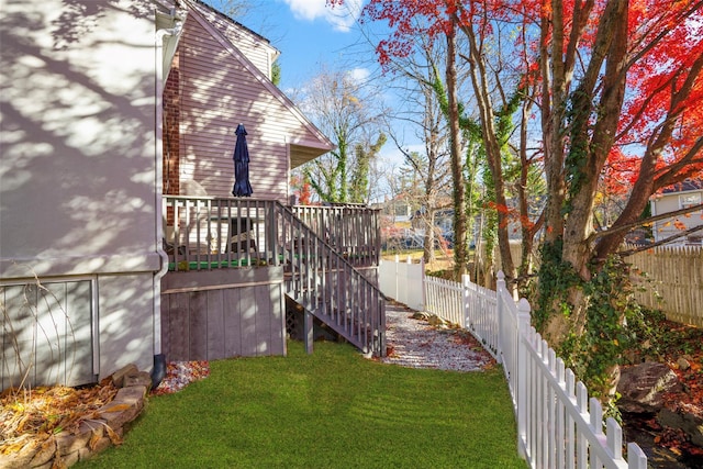 view of yard with a fenced backyard, a deck, and stairs