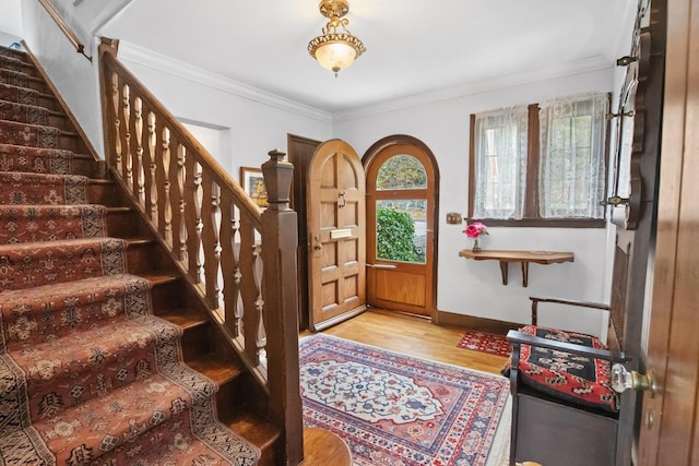 foyer featuring crown molding, stairway, wood finished floors, and baseboards