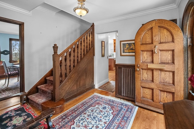 entrance foyer with stairway, wood finished floors, and ornamental molding