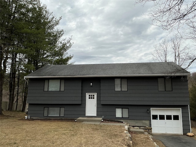 bi-level home with aphalt driveway, a garage, and a shingled roof