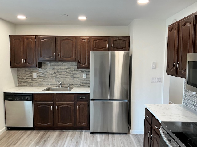 kitchen featuring light wood finished floors, dark brown cabinets, light countertops, appliances with stainless steel finishes, and a sink