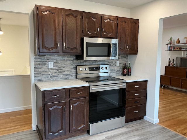 kitchen with tasteful backsplash, light wood-type flooring, dark brown cabinets, and stainless steel appliances