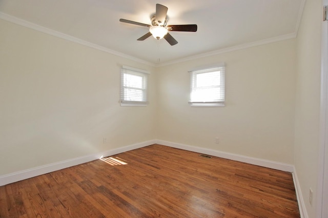 spare room with baseboards, wood finished floors, and crown molding