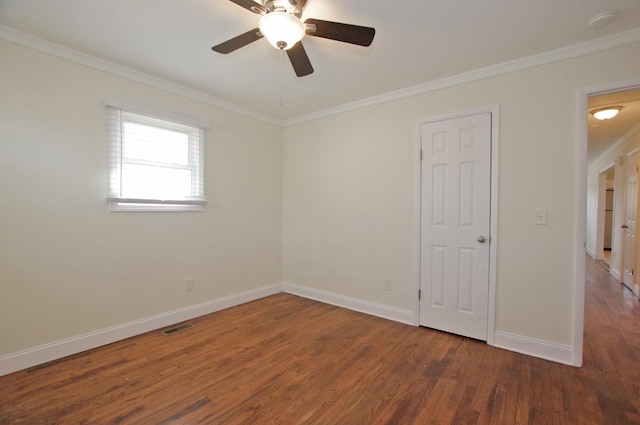 unfurnished room with visible vents, crown molding, baseboards, and wood finished floors