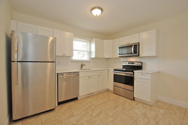 kitchen with light countertops, appliances with stainless steel finishes, a sink, and white cabinetry