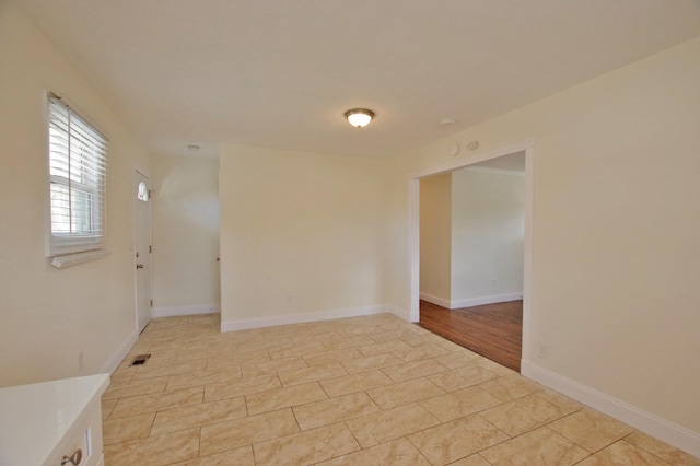 empty room featuring light tile patterned floors, baseboards, and visible vents