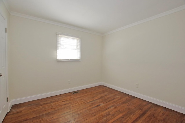 spare room with ornamental molding, wood finished floors, visible vents, and baseboards