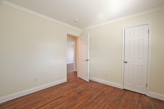 spare room with crown molding, baseboards, and wood finished floors