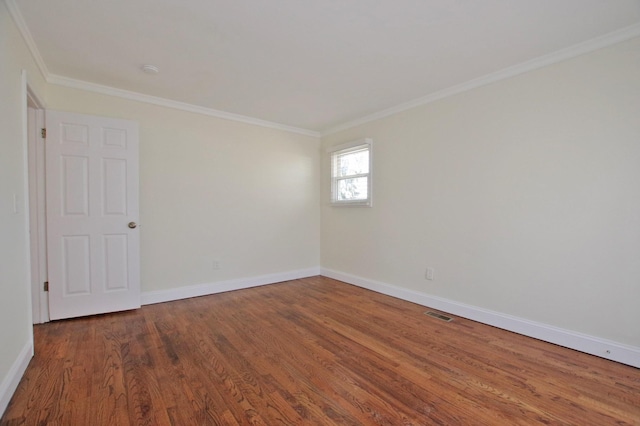 empty room featuring baseboards, wood finished floors, and crown molding