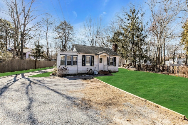 view of front of home with fence, a chimney, and a front lawn