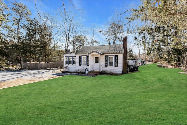 view of front of home featuring a shingled roof, a chimney, fence, and a front yard