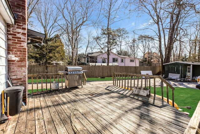 deck featuring a fenced backyard, area for grilling, a lawn, and an outbuilding