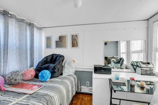 bedroom featuring a baseboard heating unit and dark wood-style floors