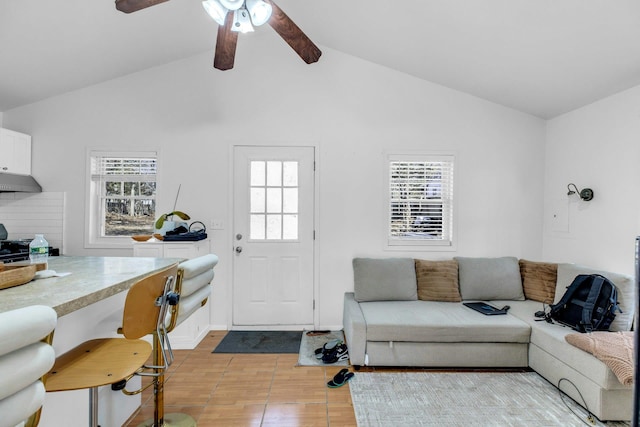 living room featuring lofted ceiling with beams, light wood-type flooring, a ceiling fan, and a wealth of natural light