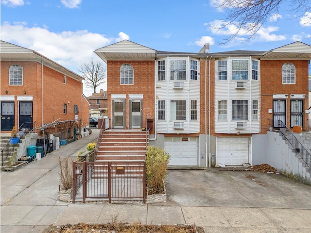 townhome / multi-family property with driveway, brick siding, and an attached garage