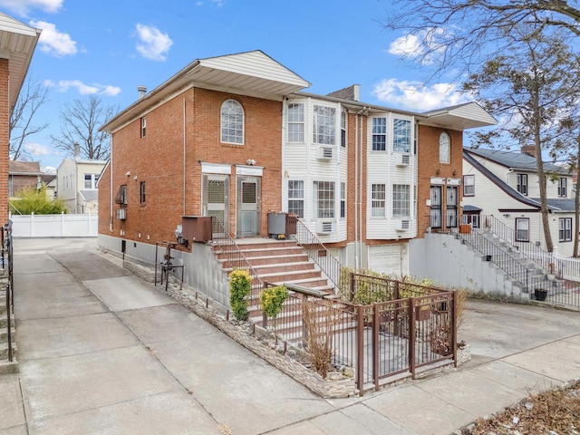 view of front of home featuring fence, concrete driveway, and brick siding