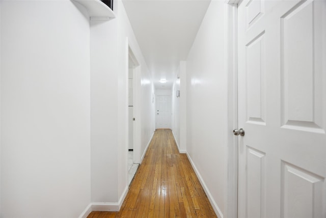 hallway with light wood-type flooring and baseboards