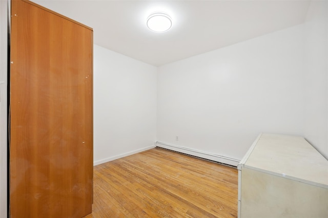 unfurnished room featuring light wood finished floors, baseboards, and a baseboard heating unit