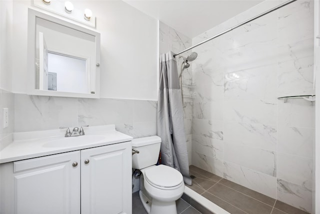 bathroom with tile walls, a tile shower, vanity, and toilet