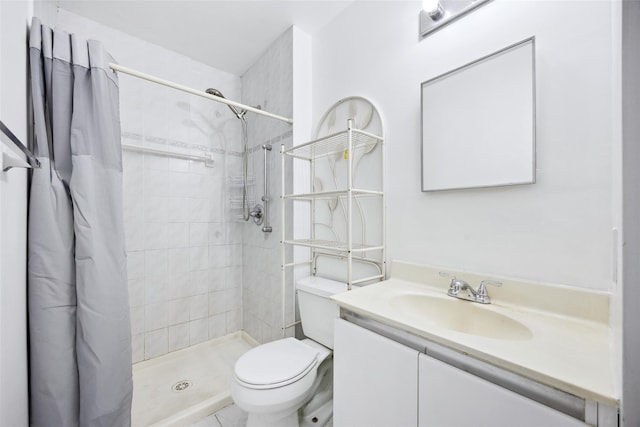 full bath featuring toilet, tiled shower, and vanity