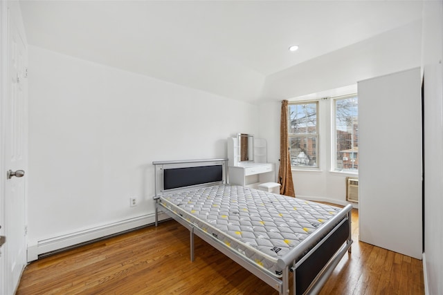 bedroom with a baseboard heating unit, recessed lighting, and wood finished floors