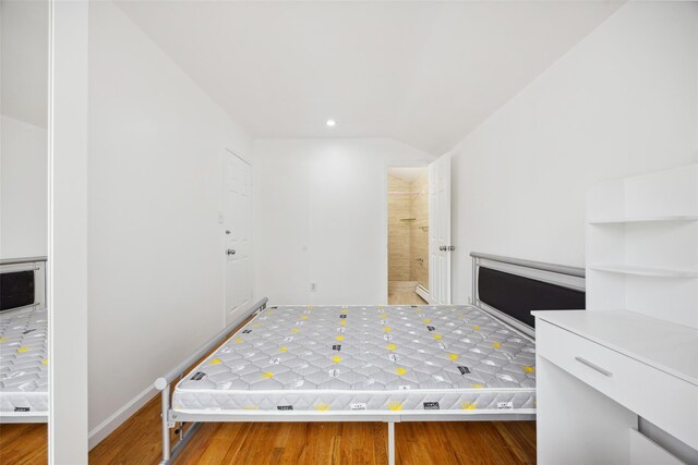 unfurnished bedroom featuring lofted ceiling, baseboards, wood finished floors, and recessed lighting