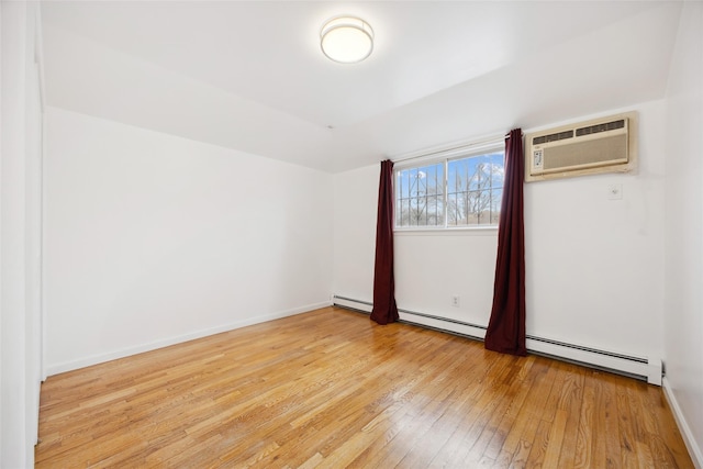 empty room featuring a baseboard radiator, wood-type flooring, a wall mounted air conditioner, and baseboards