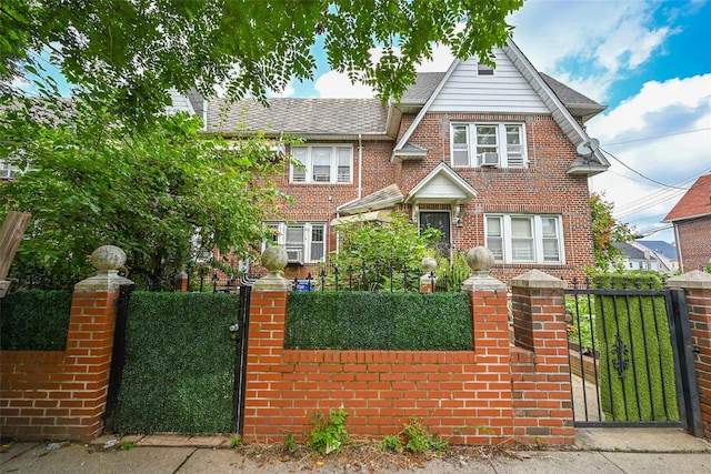 english style home featuring a fenced front yard, a gate, and brick siding