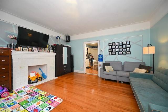 living area with baseboards, a fireplace, and light wood-style floors