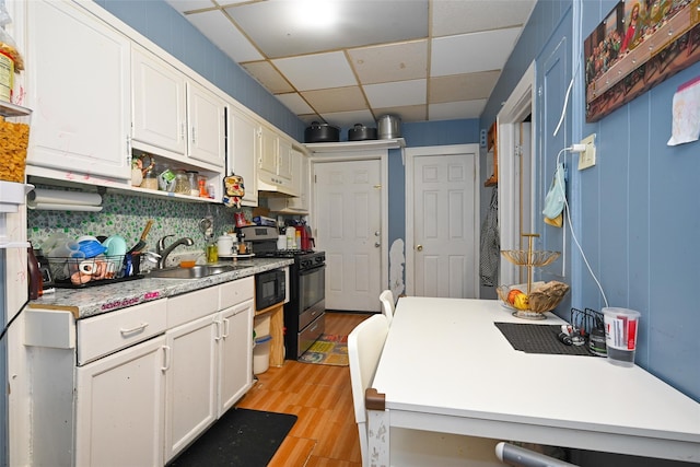 kitchen with light countertops, gas stove, white cabinets, and a sink