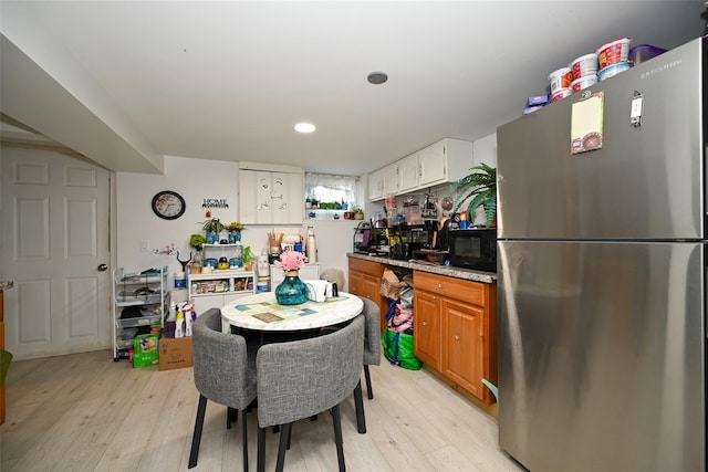 kitchen with brown cabinets, light wood-style flooring, freestanding refrigerator, white cabinetry, and black microwave