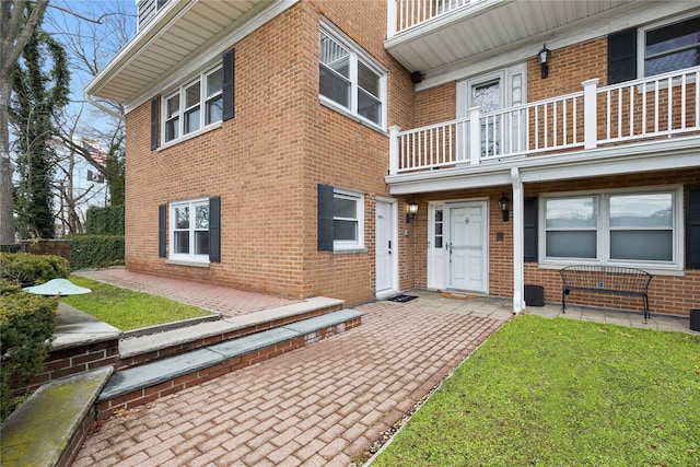 exterior space featuring a front yard, brick siding, and a balcony