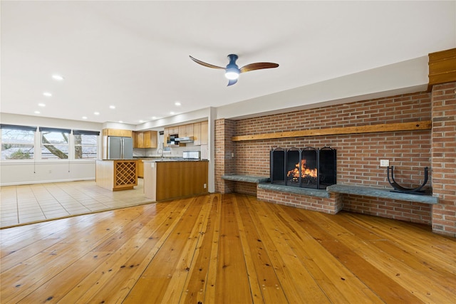 unfurnished living room with recessed lighting, a fireplace, light wood finished floors, and ceiling fan