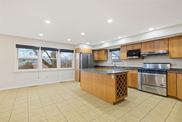 kitchen with stainless steel appliances, a center island, brown cabinetry, and under cabinet range hood