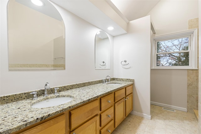 bathroom with double vanity, baseboards, a sink, and recessed lighting