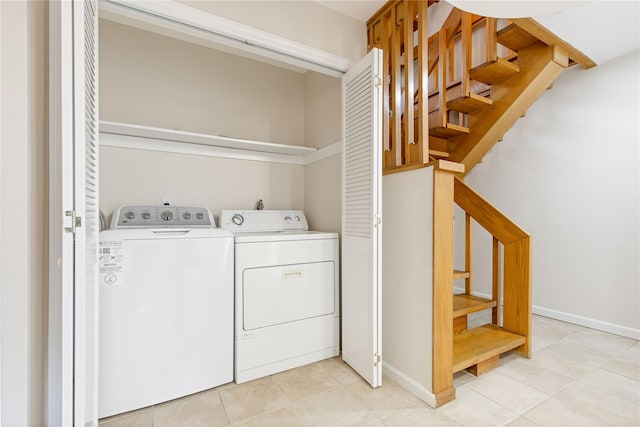 washroom with washing machine and dryer, laundry area, baseboards, and light tile patterned floors