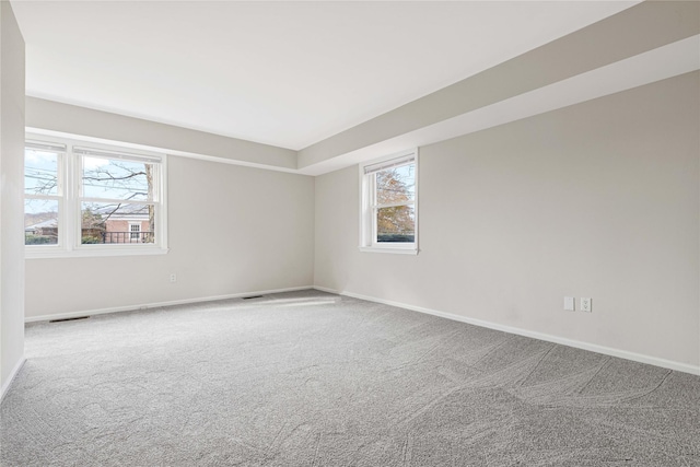 spare room featuring carpet floors, visible vents, and baseboards