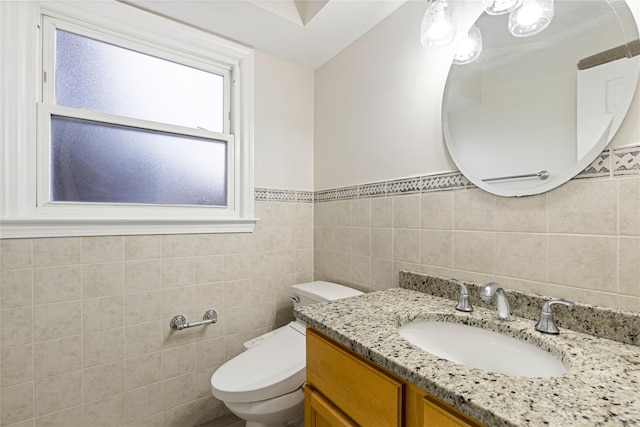 bathroom featuring toilet, vanity, and tile walls