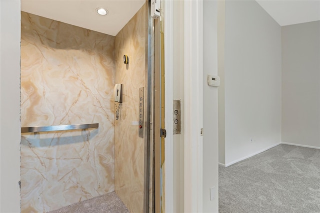 bathroom featuring baseboards, a marble finish shower, and elevator