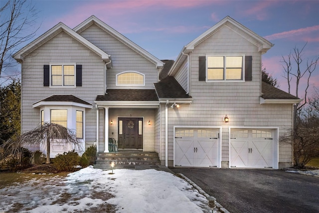 view of front of home featuring an attached garage, a shingled roof, and aphalt driveway