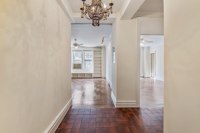 hall with baseboards, ornamental molding, a chandelier, and built in features