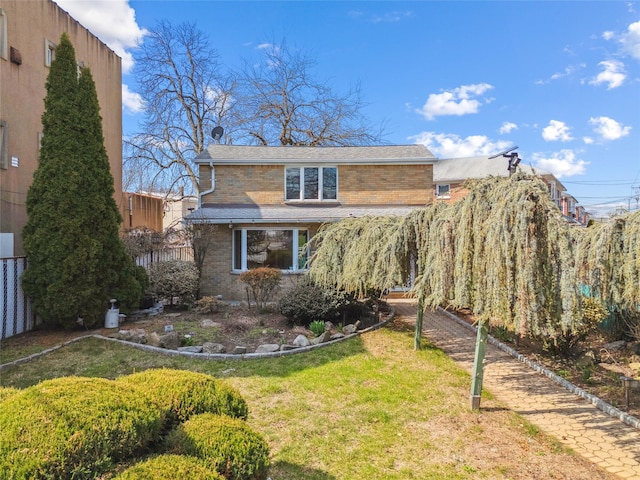 exterior space with a yard, brick siding, and fence