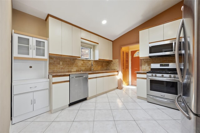kitchen featuring vaulted ceiling, appliances with stainless steel finishes, a sink, light countertops, and decorative backsplash