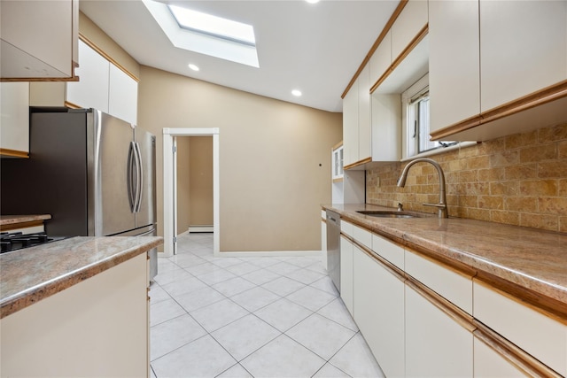 kitchen with tasteful backsplash, a sink, appliances with stainless steel finishes, white cabinetry, and a skylight